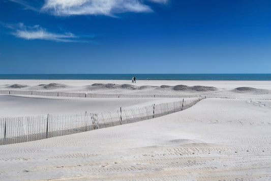 Two people walking on Jones Beach on a clear day.